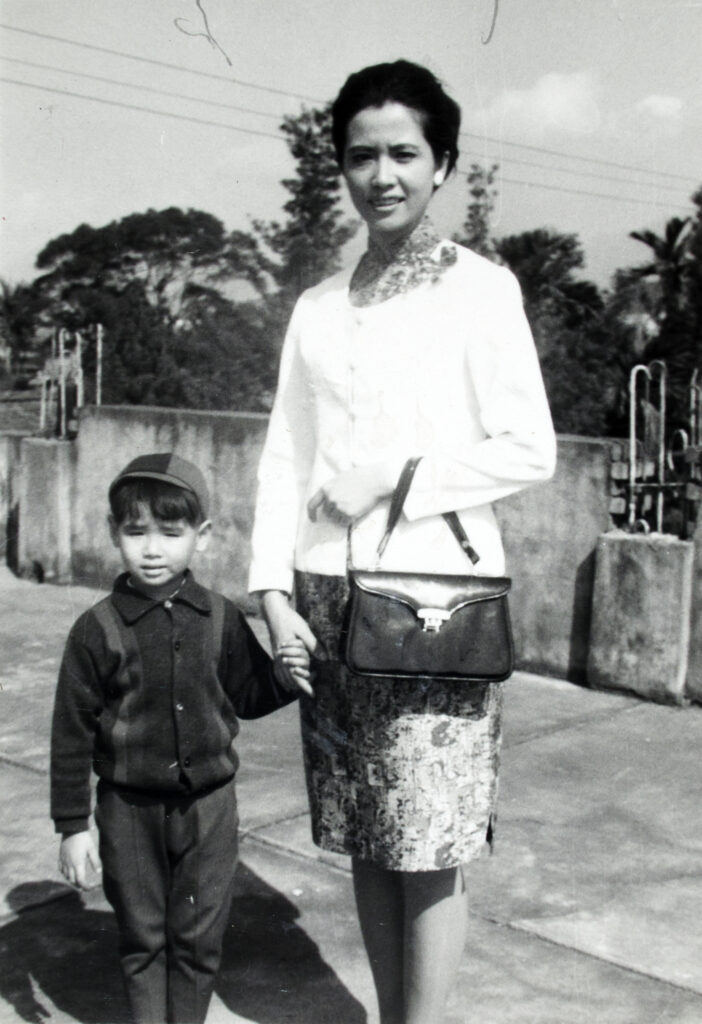 Black and white photograph of Lee Mingwei as a child standing alongside his mother.